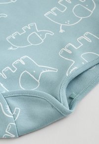 Heledsinine ühes tükis riietus, millel on mänguline valge elevanti muster. Pehme ja veniv kangas, ümmargune kaelus ja kindlad nööbiriivid all.