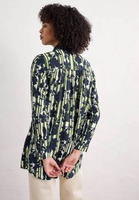Chemise à manches longues ornée d'un motif floral en rayures bleu marine et vert, fabriquée en tissu léger, avec un dos à boutons et une coupe décontractée.