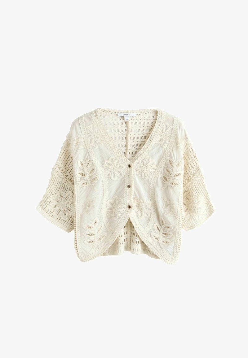 Cardigan in maglia uncinetto color crema con motivi floreali, maniche corte larghe e tre bottoni anteriori.