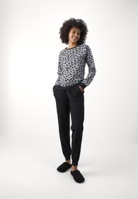 Leopardmönstrad sweatshirt i grått och svart, kombinerad med svarta skräddarsydda byxor och svarta fluffiga tofflor. Slät tygkvalitet, avslappnad passform.