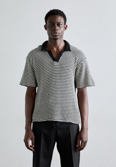 Sort og hvid houndstooth mønster kortærmet polo skjorte med sort krave, let løs pasform og tekstureret vævet stof.