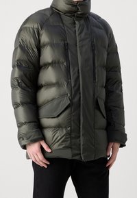 Chaqueta de abrigo verde con un alto cuello, cierre frontal con cremallera y bolsillos laterales. Presenta un acabado acolchado y puños elásticos para mayor calidez.