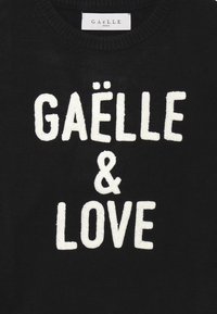 Maglione nero a maglia con testo ricamato bianco "GAËLLE & LOVE", dotato di scollo rotondo e polsini a costine.
