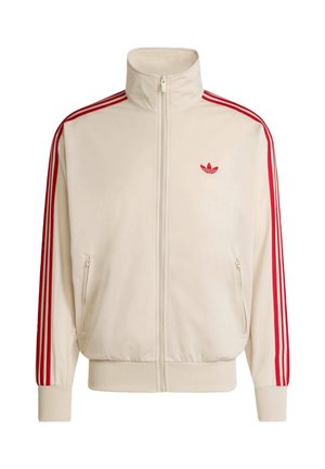 Kremowa bluza sportowa na zamek błyskawiczny z czerwonymi paskami na rękawach i czerwonym logo na lewej piersi, wyposażona w ściągacze na rękawach i w pasie.