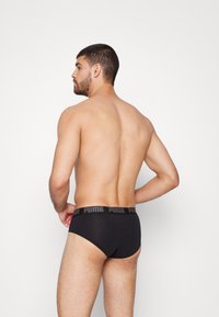 Schwarze Slips mit einem Markenbund. Hergestellt aus einem glatten, elastischen Material. Verfügt über ein figurbetontes Design und minimale Abdeckung im Rückenbereich.