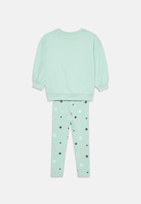 Sweatshirt in cotone verde menta con maniche lunghe, abbinato a leggings verdi menta con motivi floreali colorati in rosa, nero e arancione.
