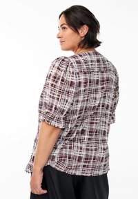 Chemisier bordeaux et blanc à motifs avec des manches courtes bouffantes, coupe décontractée et col arrondi. Tissu léger avec une finition texturée.
