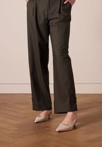 Brede, donkergrijze broeken met voorplooien en enkelboorden, gecombineerd met lichtroze slingback hakken met een spitse neus en een klein metallic detail.