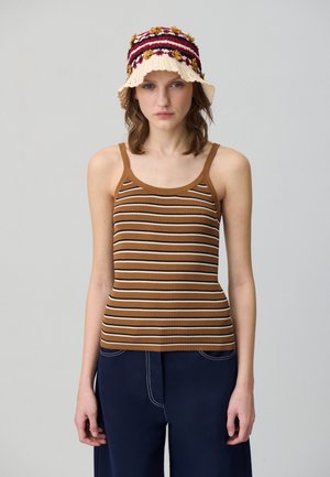 Canottiera marrone a coste con strisce orizzontali in bianco e marrone scuro. Abbinata a pantaloni a gamba larga blu navy e un cappello a secchiello all'uncinetto.