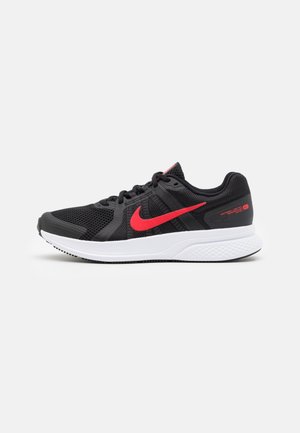 Chaussure de course noire Nike avec un swoosh rouge, semelle blanche et tige en mesh respirant, présentée sur fond blanc uni.