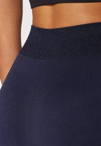 Leggings a vita alta blu navy realizzati in un tessuto elastico e testurizzato, con un dettaglio lucido in vita. Il design senza cuciture migliora la vestibilità e il comfort.