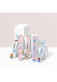 Fem farverige neglefil med Disney-tema illustrationer og Tweezerman-mærkning, vist mod hvide geometriske blokke.