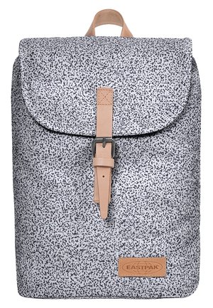 Weißer Rucksack mit kleinen schwarzen Sprenkeln, beigem Schnallenriemen an der vorderen Klappe und "Eastpak"-Logoaufnäher am unteren Ende.
