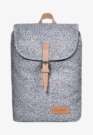 Mochila blanca con pequeñas motas negras, correa con hebilla beige en la solapa frontal y parche con el logo "Eastpak" en la parte inferior.