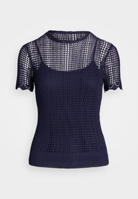 Námořnický pletený top s krátkým rukávem, který se vyznačuje texturovaným otevřeným tkaním, vlněnými okraji rukávů a přiléhavým střihem.