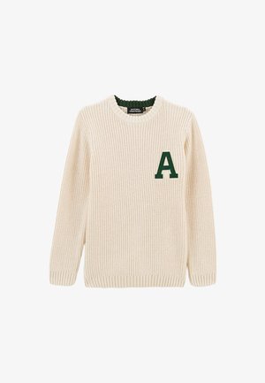 Pull en tricot crème avec un col côtelé. Présente une lettre "A" verte sur la poitrine gauche ainsi que des poignets et un ourlet côtelés. Texture douce.