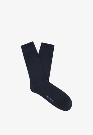 Para czarnych skarpetek za kostkę z prążkowanymi ściągaczami i małym, jasnoniebieskim logo w pobliżu palców na białym tle.