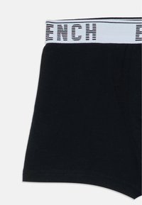 Boxers noirs avec une ceinture blanche présentant un texte rayé noir écrivant partiellement "FRENCH".