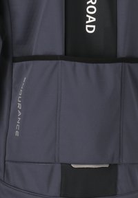 Marinblå softshell-jacka med svarta accenter, som har en reflekterande logotyp, flera fickor och ett slätt, något texturerat tyg.