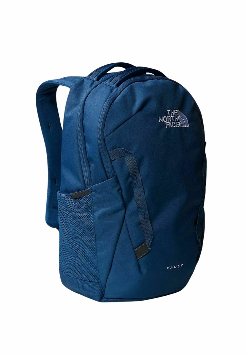 Námorně modrý batoh vyrobený z odolné tkaniny, s polstrovanými ramenními popruhy, síťovou boční kapsou a logem North Face. Model: Vault.