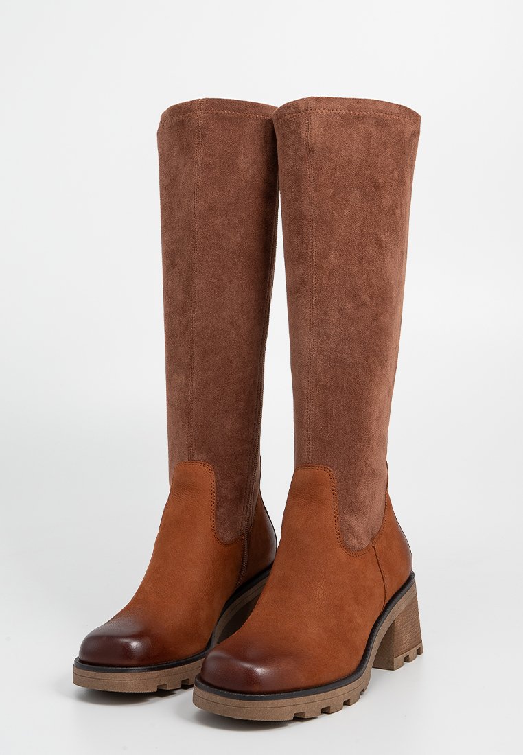 Botas marrones hasta la rodilla con una combinación de texturas lisas y de ante. Tacón ancho, punta redondeada y paneles laterales elásticos.