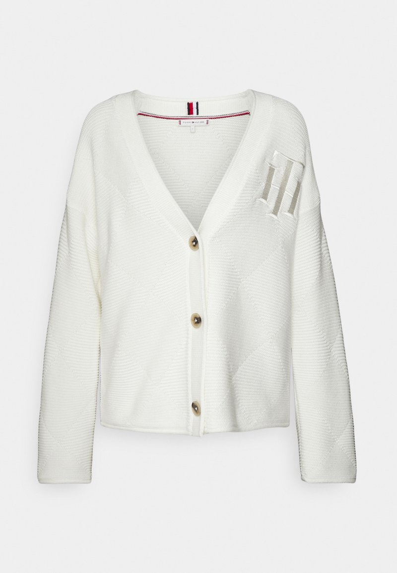 Cardigan en maille blanc avec col en V, trois boutons marron, manches longues et logo en relief "TH" sur la partie supérieure gauche de la poitrine.