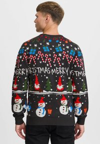 Suéter negro con motivos festivos: muñecos de nieve, árboles de Navidad, bastones de caramelo, regalos y texto navideño. Puños y dobladillo acanalados.