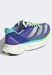 Violet sportinė avalynė su tinkliniu viršumi, neoninės žalios spalvos akcentais ir baltais dryžiais; turi lengvą padą, pažymėtą "LIGHTSTRIKE PRO."