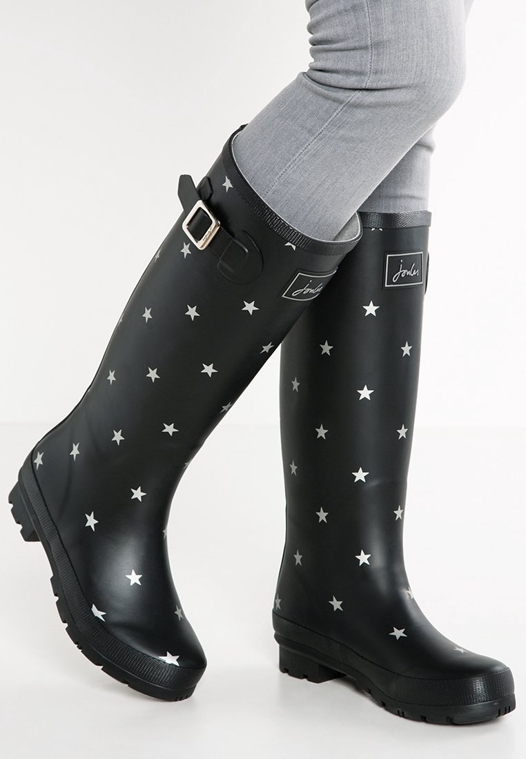 Botas de lluvia de goma negras con un patrón de estrellas plateadas, hebilla ajustable y suela texturada para mayor agarre.