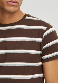 Brunrandig t-shirt med horisontella ränder i ljusrosa och blått, med rundad hals och korta ärmar. Tyget verkar mjukt och slätt.