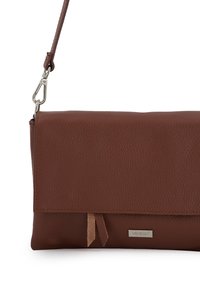 Brązowa torebka crossbody ze skórzanym teksturowanym wykończaniem, z klapką, srebrnym metalowym zapięciem oraz metką marki Venezia na przodzie.