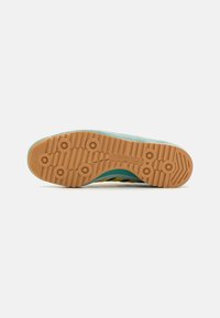 Adidas sneaker talpa textúrált gumiból készült, világosbarna színben, kör alakú tapadásmintákkal és türkizkék felső átmenettel.