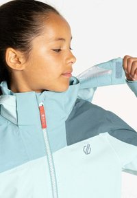 Himmelblau und türkis wasserdichte Jacke mit hohem Kragen, Frontreißverschluss und Klettverschlussmanschetten. Kleines Logo auf der Brust, glatte Textur.