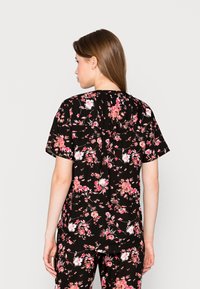 Blusa nera a fiori con maniche corte, vestibilità comoda e schiena arricciata, caratterizzata da motivi floreali rosa e bianchi.