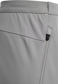 Graue Sportshorts aus atmungsaktivem Material, mit einem genähten Bund und einer seitlichen Reißverschlusstasche mit schwarzen Hardware-Details.