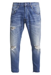 Vaqueros de mezclilla azul desvaído con desgastes y roturas, cinco bolsillos y costuras en contraste. Diseño de pierna recta, cintura de altura media.
