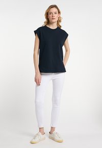 Námořnické tričko s krátkým rukávem ve spojení s bílými slim-fit džíny a bílými teniskami. Tričko má kulatý výstřih a uvolněný střih.