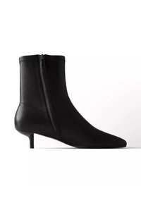 Bottine en cuir noir avec fermeture éclair sur le côté et petit talon kitten, bout pointu, présentée sur fond blanc.