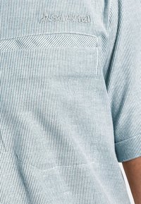 Gestreept shirt met korte mouwen met een subtiel blauw-wit patroon, gemaakt van lichtgewicht stof met een logo-stiksel nabij de zak.