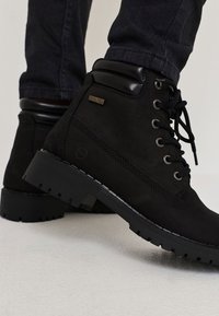 Svarta anklarstövlar i texturerat syntetmaterial, med metallöglor, en vadderad krage och en robust gummisula med mönster.