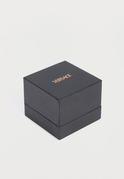 Μαύρο τετράγωνο κουτί δώρου με υφασμένη επιφάνεια, χρυσό λογότυπο «VERSACE» στην κορυφή, κλειστό, απομονωμένο σε λευκό φόντο.