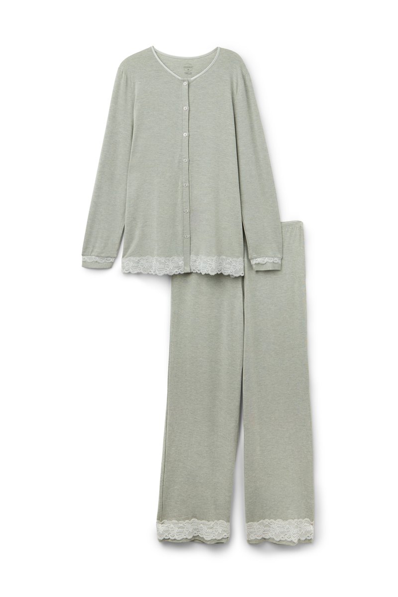 Blusa de botón de manga larga en gris claro con dobladillo de encaje, combinada con pantalones a juego que presentan encaje en la parte inferior de las piernas.