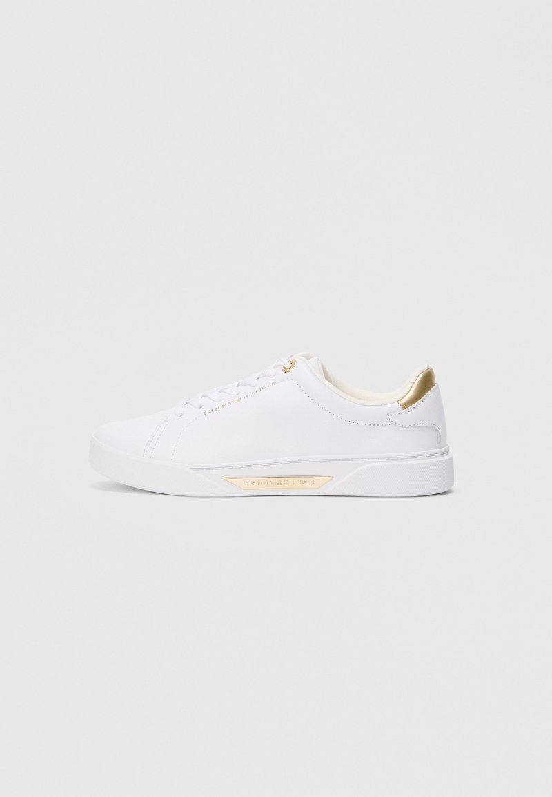 Fehér alacsony fazonú sneaker arany díszítéssel a saroknál, a fűzőlyukaknál és az oldalon, Tommy Hilfiger márkázással a felső részen és a talpon.