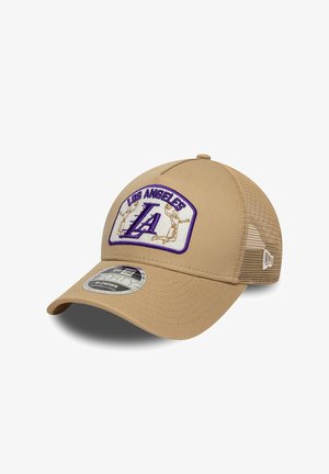 Gorra trucker beige con parte trasera de malla, que presenta un parche de Los Ángeles con letras "LA" en púrpura y siluetas de jugadores de baloncesto.