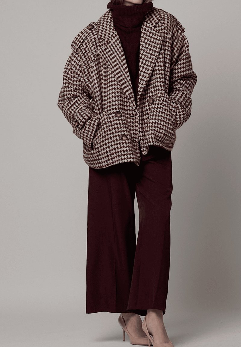 Chaqueta oversize de patrón pata de gallo marrón y blanco con botones dobles, combinada con pantalones anchos color burdeos oscuro y tacones beige.