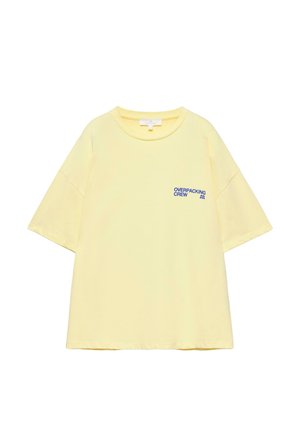 Svetloč žlté tričko s krátkym rukávom a okrúhlym výstrihom s modrým nápisom "OVERPACKING CREW" na ľavej strane hrudníka.