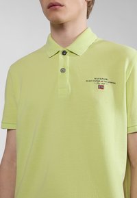 Polo shirt verde chiaro realizzato in tessuto testurizzato, con colletto a due bottoni, logo ricamato e maniche corte.