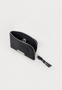 Pochette nera con zip e dettagli in argento, con tirazip intrecciato, parzialmente aperta su uno sfondo chiaro.