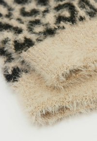 Beige flauschiger Schal mit einem schwarzen Leopardenmuster und subtilen goldenen Akzenten, weicher Textur und einem geschichteten Look mit fransigen Kanten.