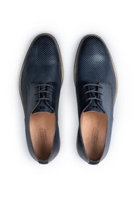 Paire de chaussures habillées en cuir bleu foncé perforé avec lacets, semelles intérieures marron et semelles extérieures marron clair sur fond blanc.